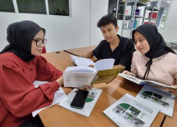 Rajab Vadil, Indah Amalia Ramadhan, dan Devti Marna Syafitri, berdiskusi di perpustakaan TPK Unri.