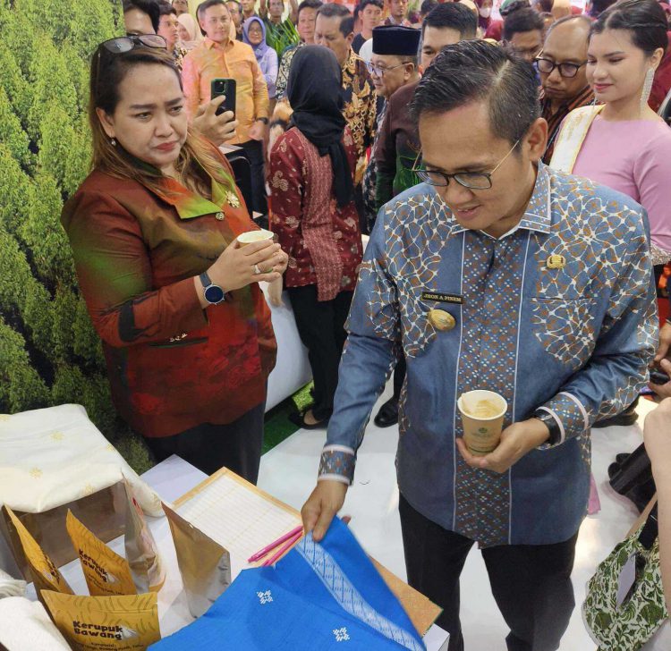 Penjabat (Pj) Bupati Pelalawan Dr.Jhon Armedi Pinem saat meninjau stand RAPP dan APR di Helat Pelalawan ke-25. Pj Bupati memperhatikan tenun dari viscose rayon karya mitra bina APR.