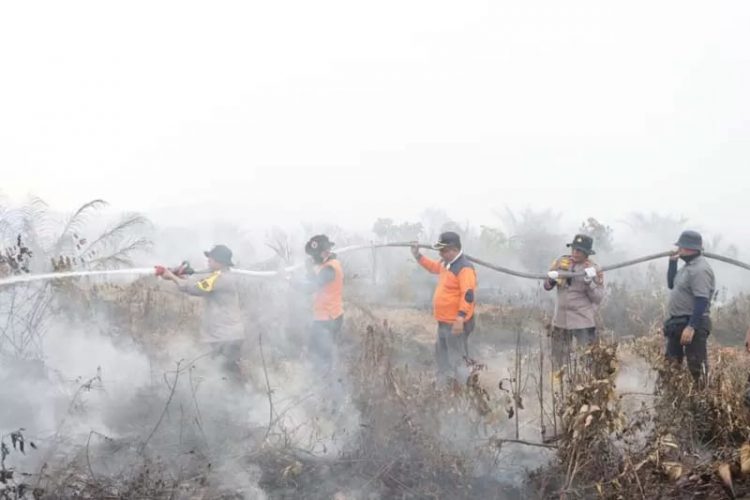 Kapolres Siak AKBP Asep Sujarwadi melakukan pemadaman api di Kampung Buantan Besar, Kecamatan Siak, Selasa (30/7/2024). (SEKWAN DPRD SIAK )