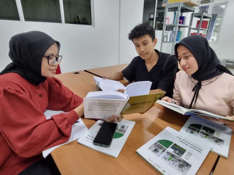 Rajab Vadil, Indah Amalia Ramadhan, dan Devti Marna Syafitri, berdiskusi di perpustakaan TPK Unri.